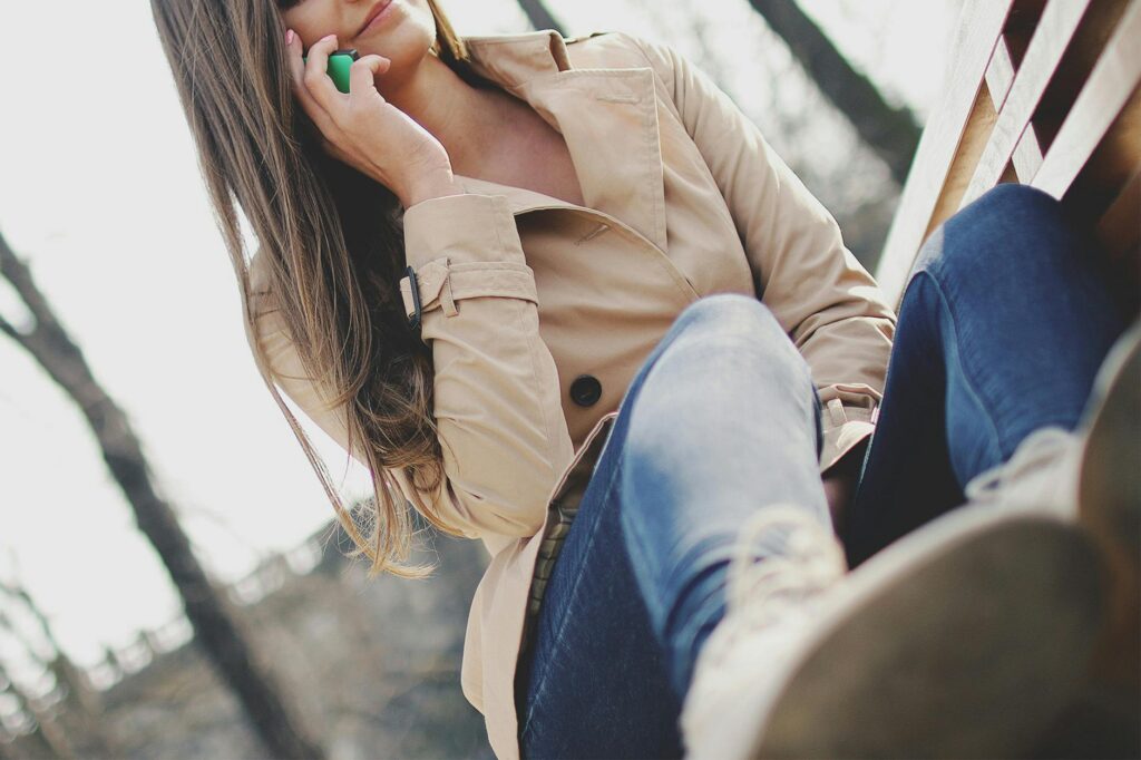 Fashionable woman in casual outfit chatting on a smartphone outdoors.